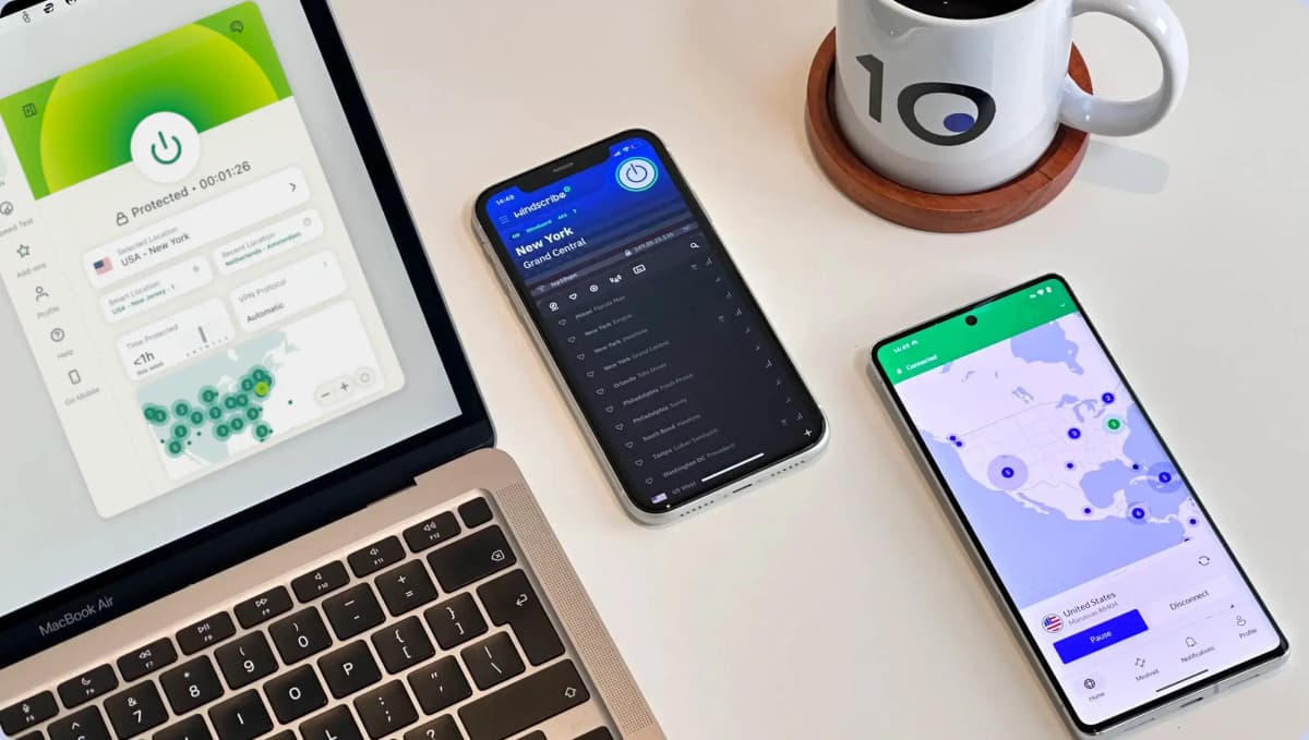 Three of our top-rated VPNs running on a laptop and two smartphones next to a Top10VPN-branded mug.