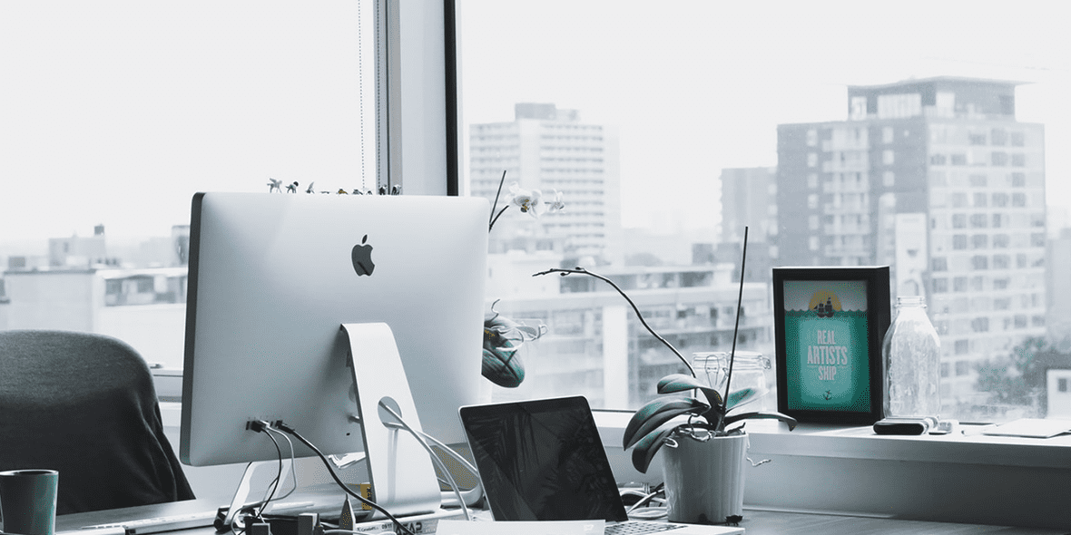 Back of an iMac in front of a window looking out at a city Back of an iMac in front of a window looking out at a city