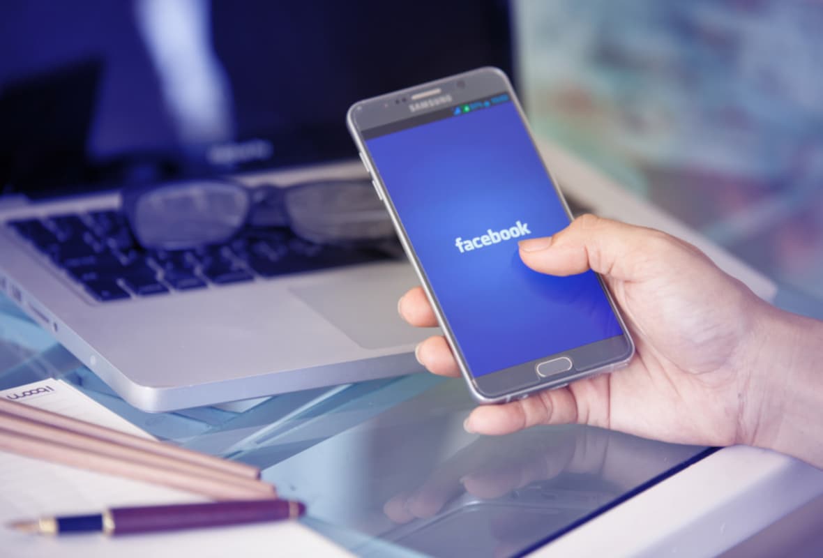 Person Holding Phone with Facebook Logo on the Screen Person Holding Phone with Facebook Logo on the Screen