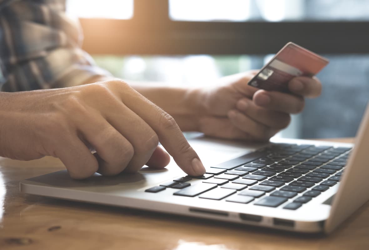 Person Holding Credit Card and Typing on a Laptop Computer Person Holding Credit Card and Typing on a Laptop Computer