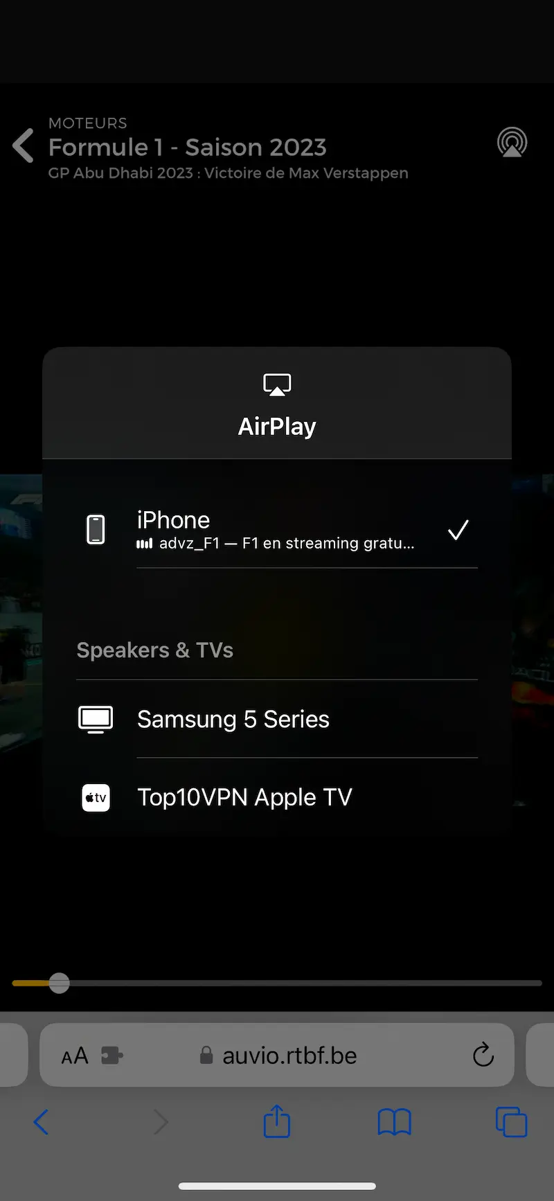 Interfejs platformy streamingowej RTBF Auvio z otwartym menu AirPlay, pokazujący F1 jako wybrany materiał. Urządzenia na liście to „iPhone”, „Samsung 5 Series” oraz „Top10VPN Apple TV”. Interfejs wyświetla również adres „auvio.rtbf.be” u dołu ekranu.